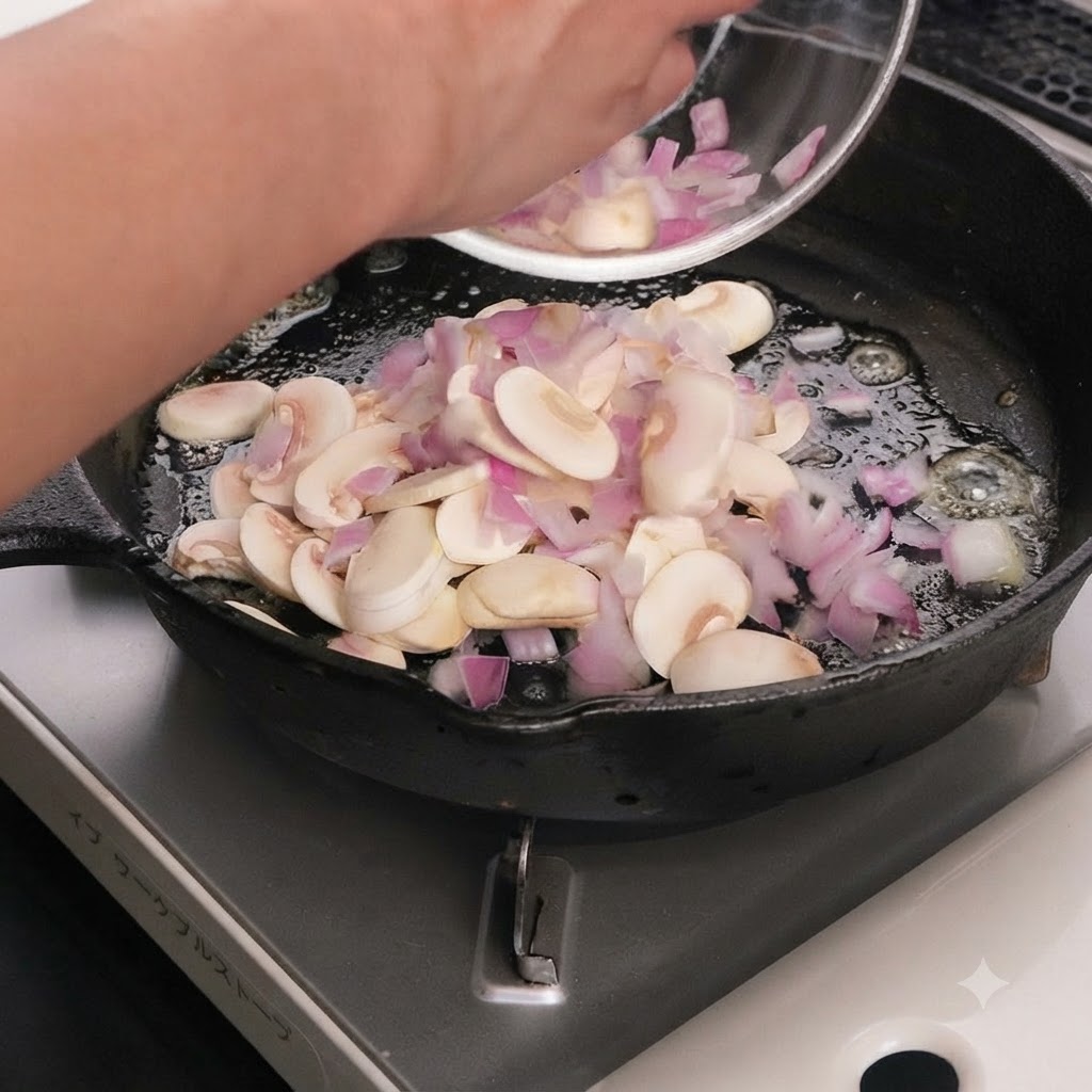 Des champignons tranchés et des oignons rouges cuisant dans du beurre fondu à lintérieur dune poêle en fonte.