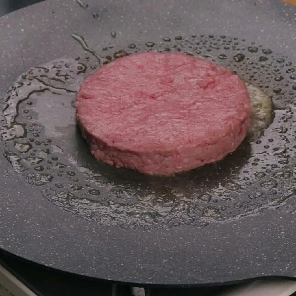 Un steak de bœuf cru cuisant dans le beurre à lintérieur dune poêle chaude.