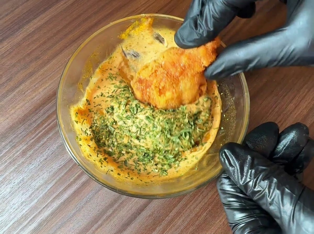 Du persil fraîchement haché saupoudré sur un bol de sauce burger préparée alors quun morceau daliment frit y est trempé.