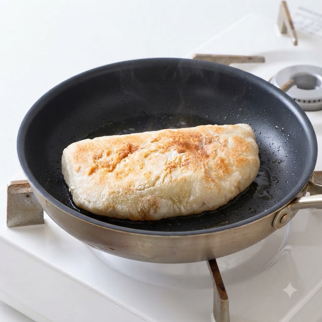 Moitiés de pain ciabatta dorant dans lhuile dans une poêle jusquà devenir croustillantes.