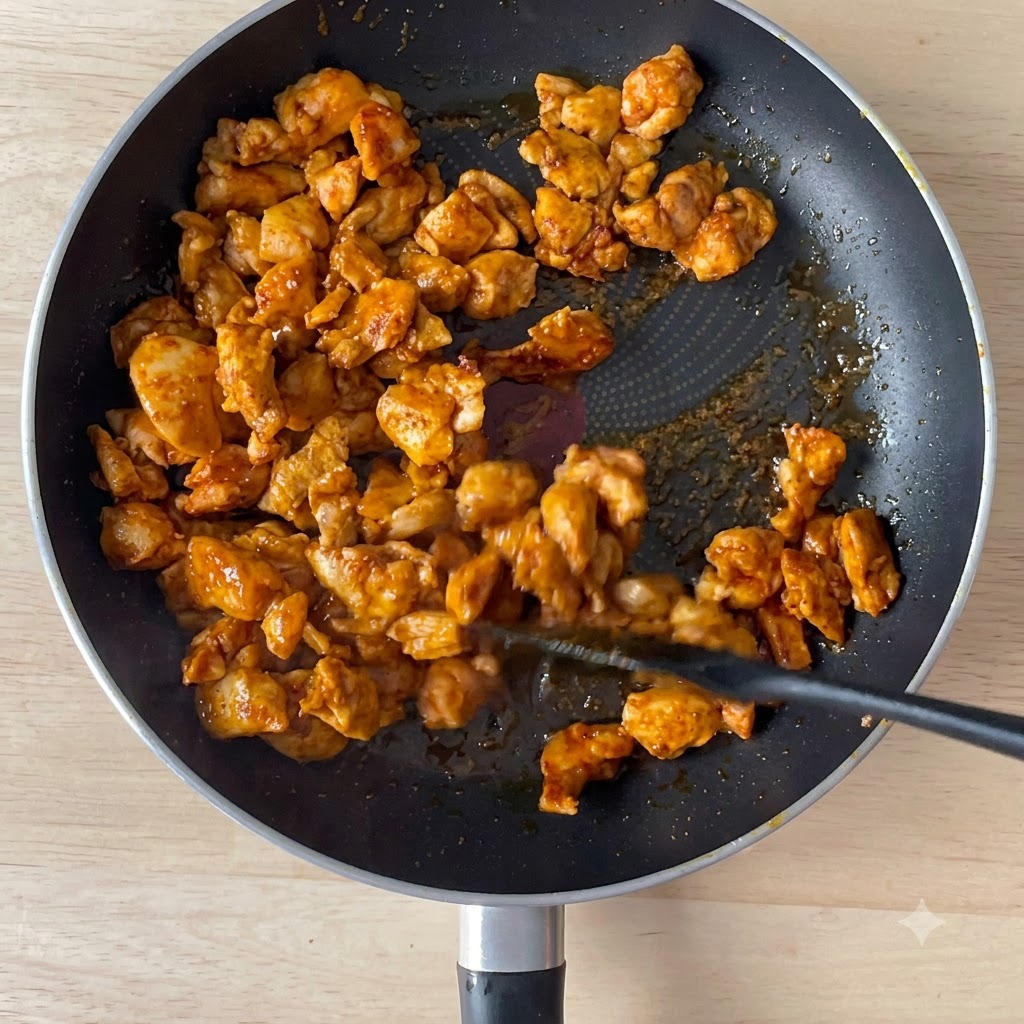 Sauce soja versée dans une poêle contenant des morceaux de poulet dorés.