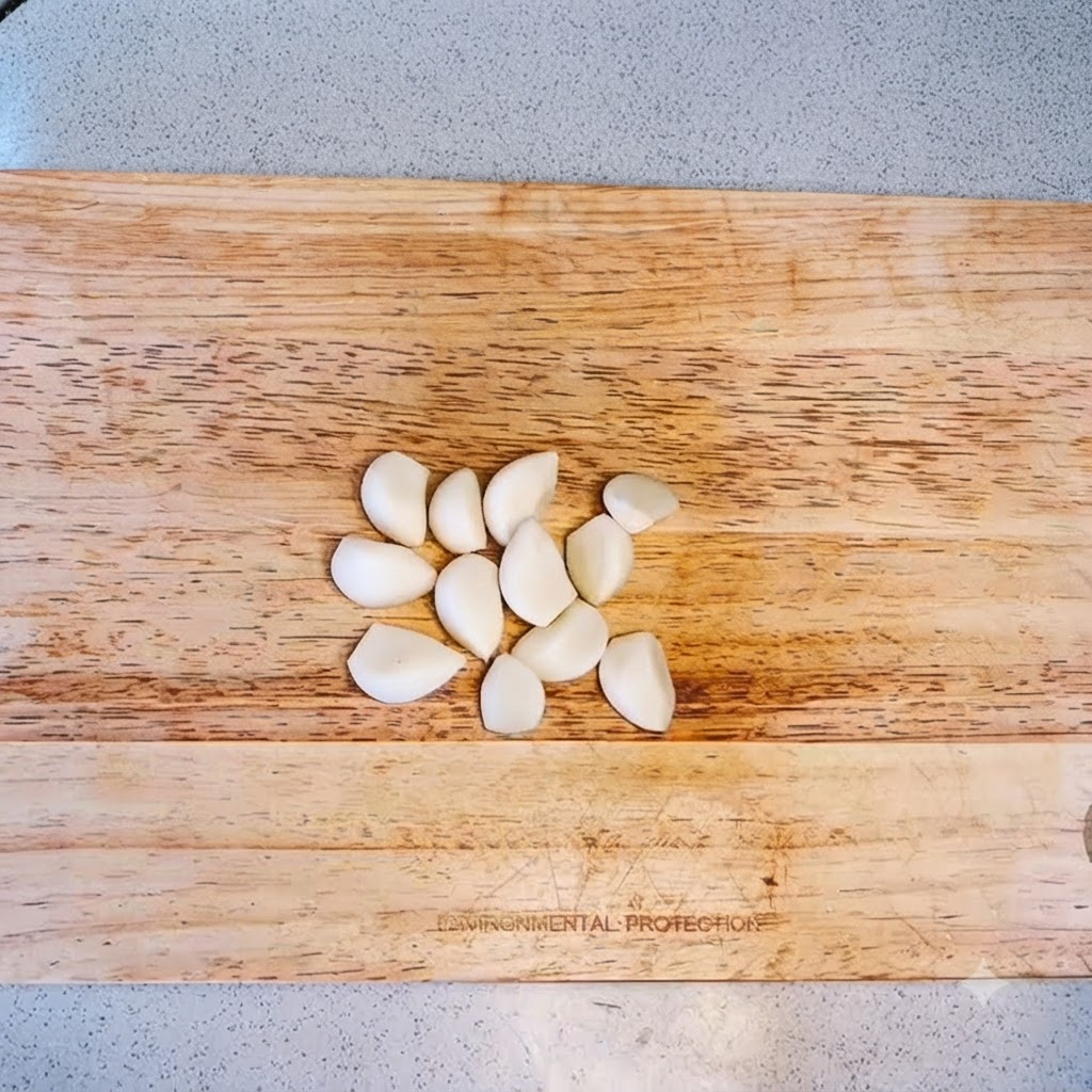 Gousses dail disposées sur une planche à découper en bois prêtes à être hachées.