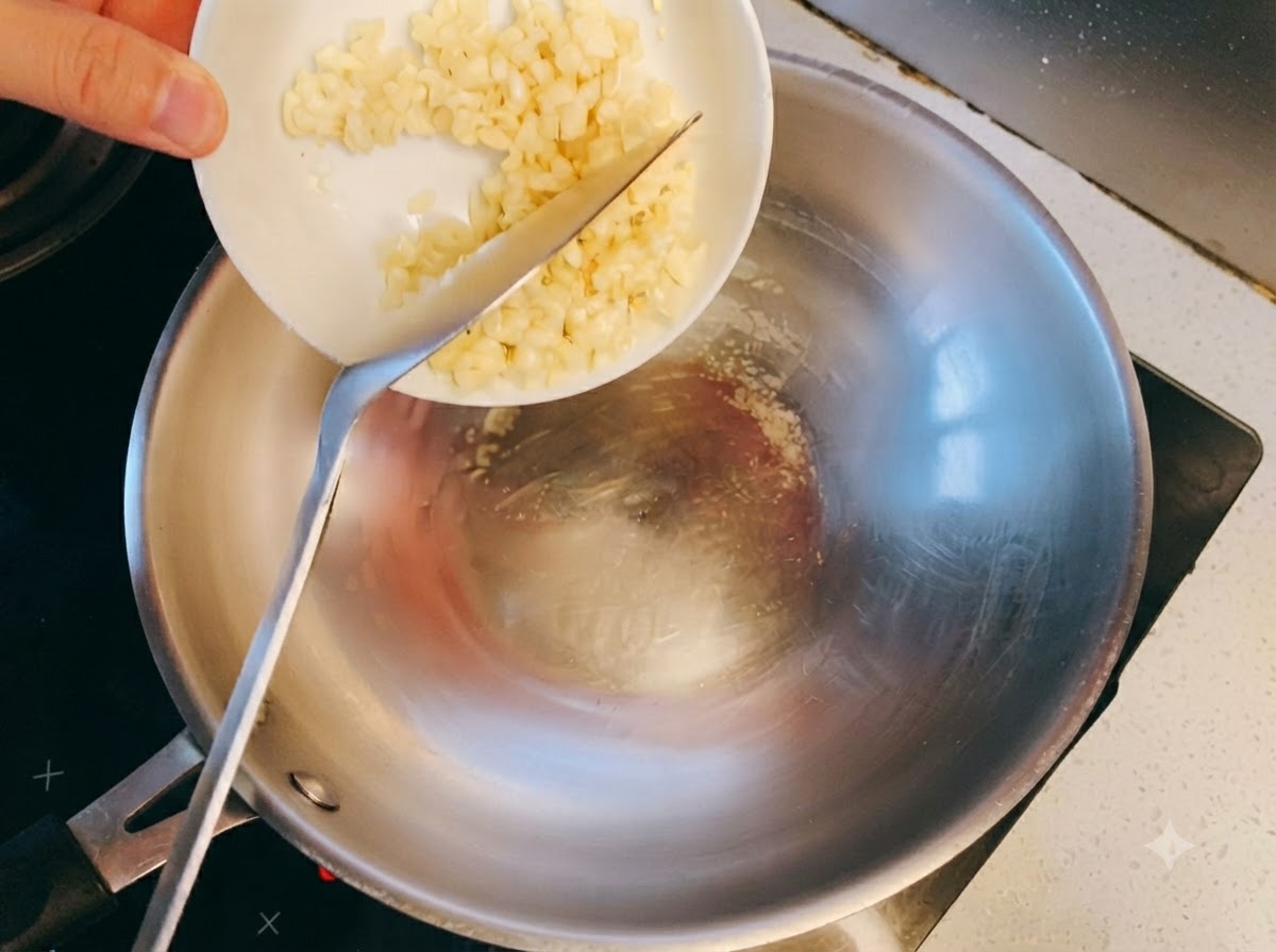 De lail haché touchant lhuile chaude dans un wok en acier inoxydable et commençant à dorer.